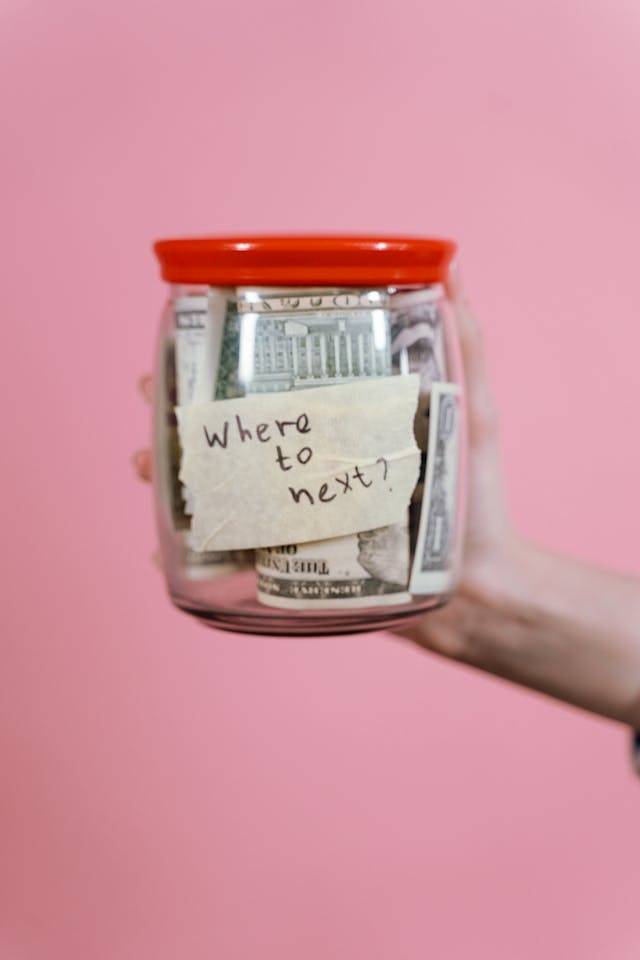 Where to next? Money in jar that was saved from budget travel tips.