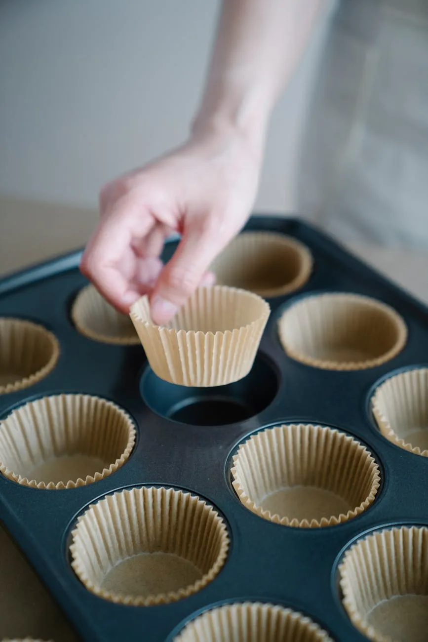 person putting cupcake liners on a tray to make mini meatloaf