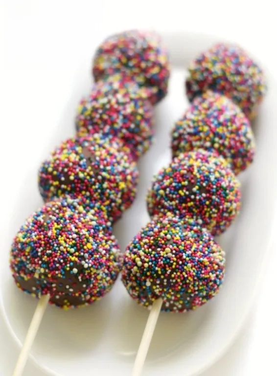
Colorful chocolate cake pops coated in vibrant rainbow sprinkles, neatly arranged on skewers and served on a white platter. This playful Valentine's Day dessert is a fun and festive treat for chocolate sweets enthusiasts of all ages.