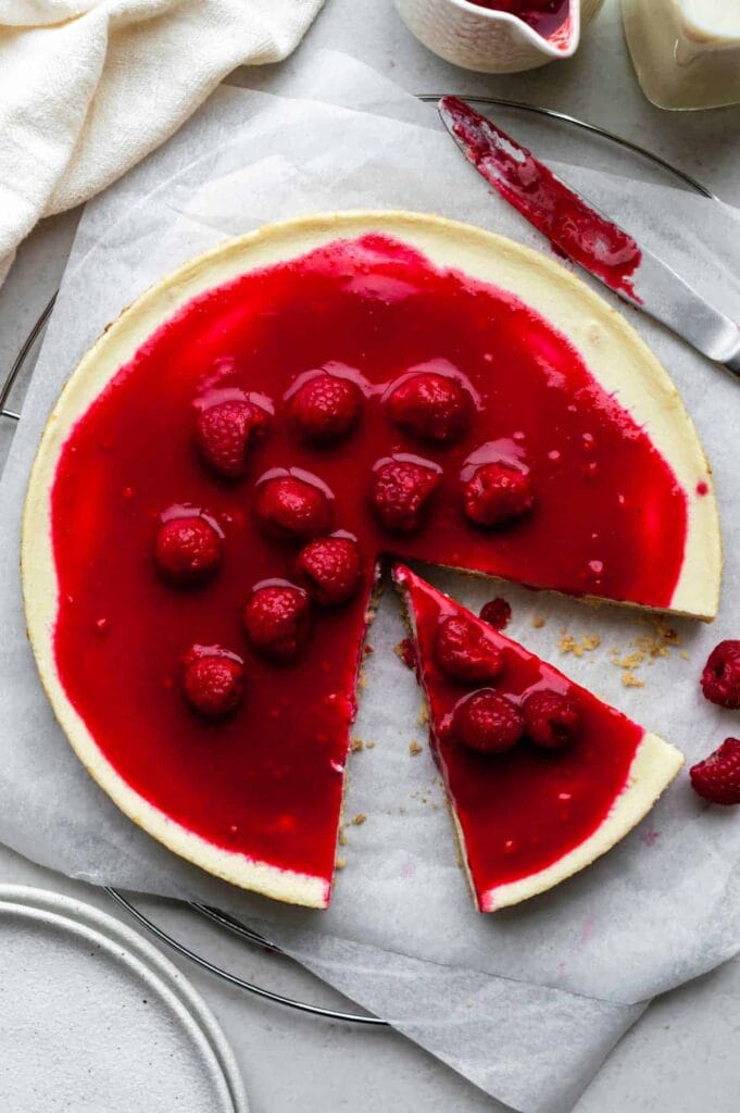 Easy Cheesecake Without Cream Cheese topped with a vibrant raspberry glaze and fresh raspberries, a stunning and budget-friendly choice for Valentine's Dessert Ideas.