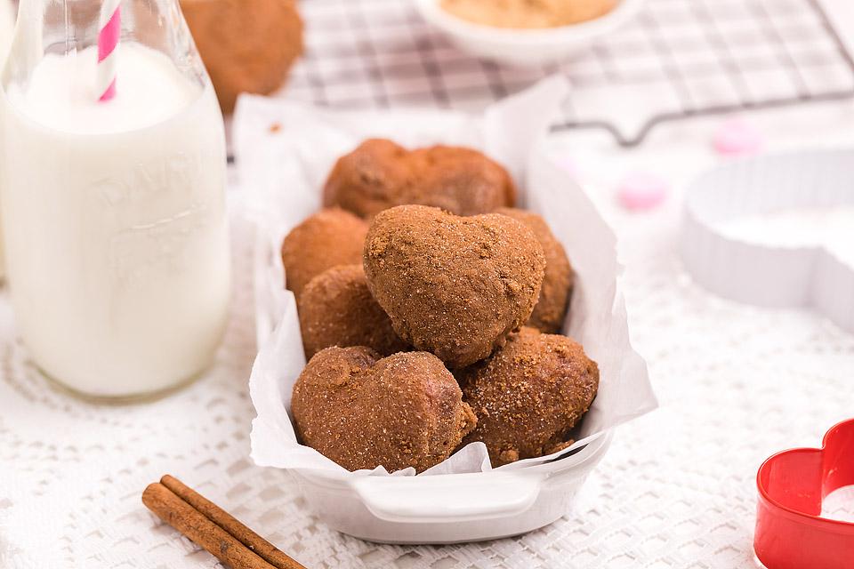 Heart-Shaped Mini Sugar Donut Holes coated in cinnamon sugar, served in a white dish, a delightful and festive choice for Valentine's Dessert Ideas.