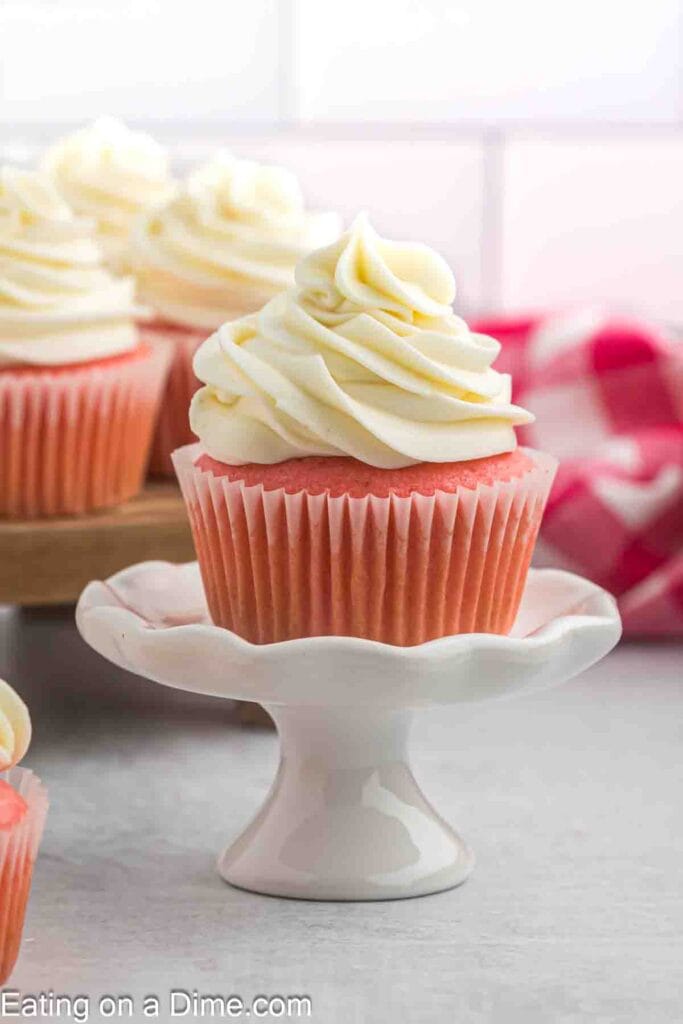 Pink Velvet Cupcake topped with fluffy cream cheese frosting, displayed on a white pedestal, a festive and charming option for Valentine's Dessert Ideas.