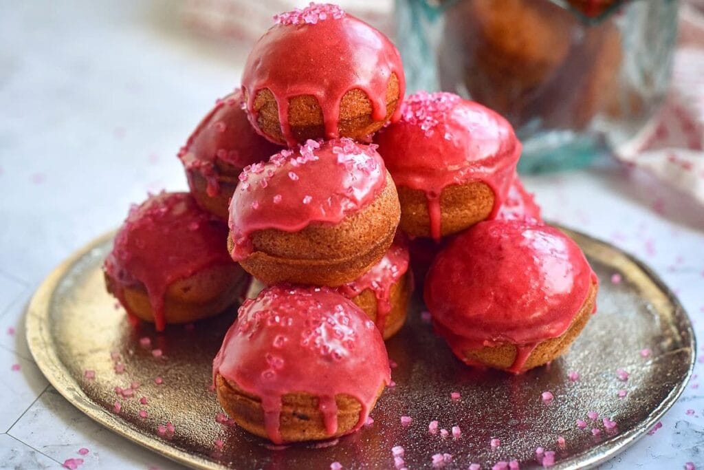 Valentine's Day Cake Balls coated in vibrant pink glaze and sprinkled with sugar crystals, a fun and festive option for Valentine's Dessert Ideas.