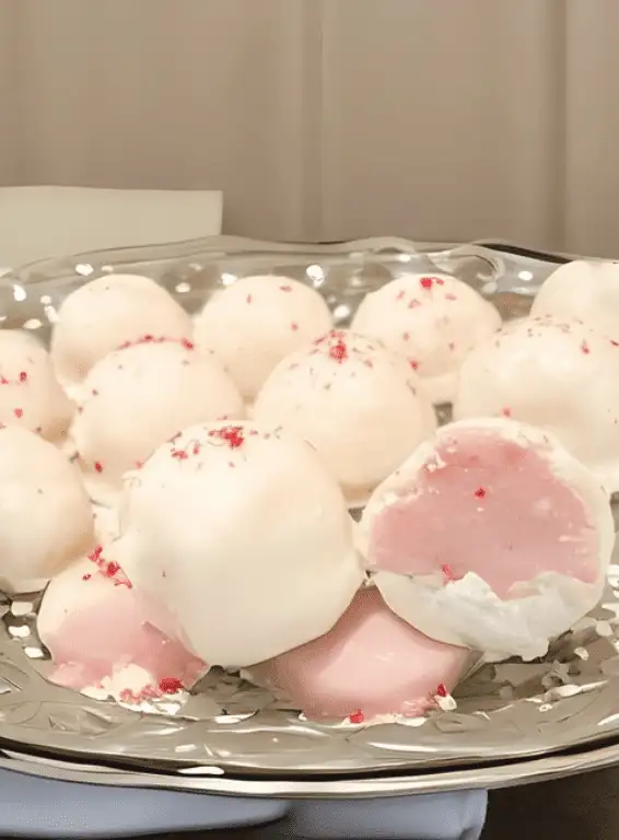 
A silver platter filled with white chocolate truffles, featuring a creamy pink center and sprinkled with delicate red accents. This elegant Valentine's Day dessert is a delightful treat for chocolate sweets lovers, perfect for sharing on a romantic occasion.