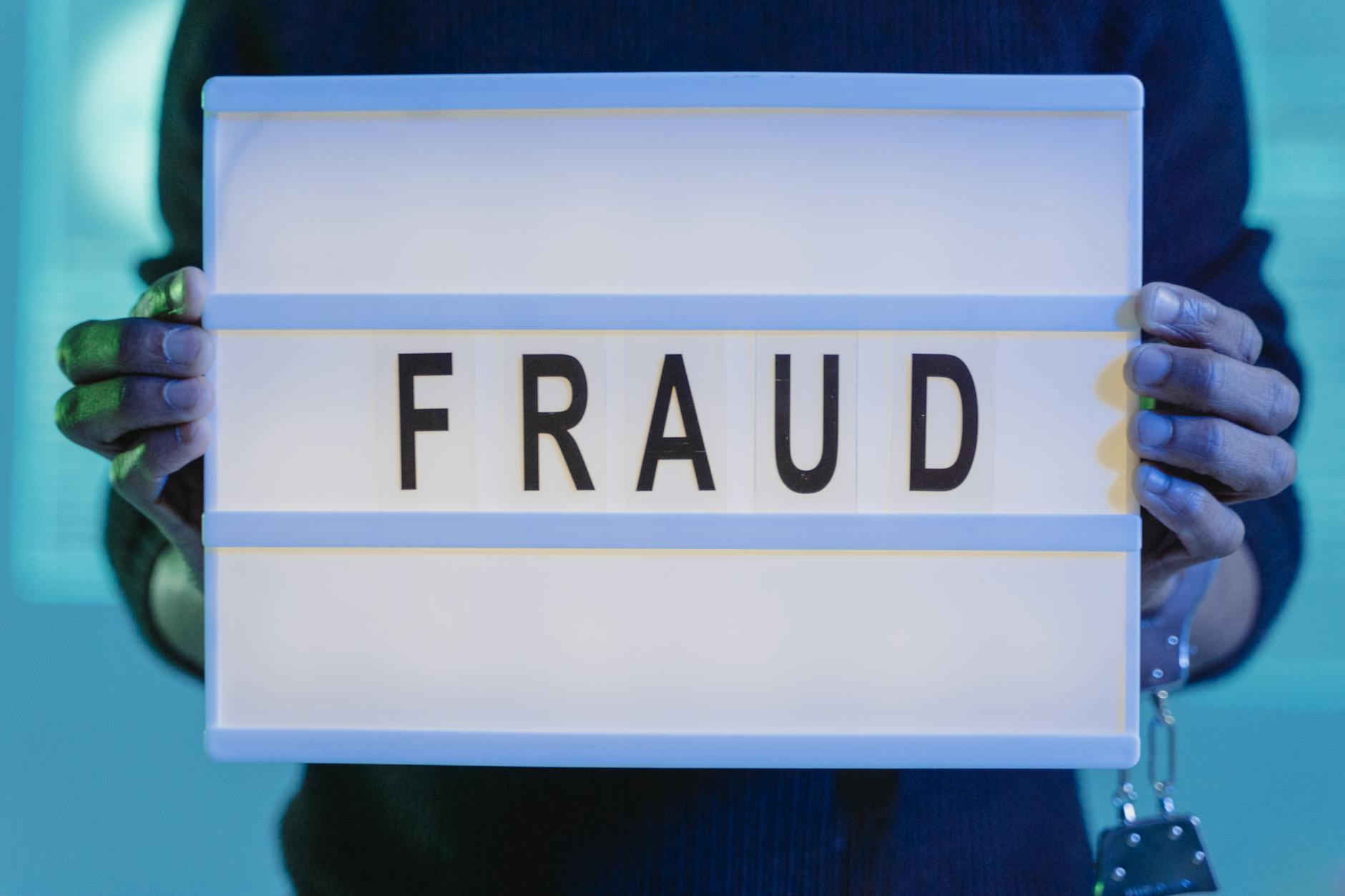 Securing Your Financial Data and Protecting Against Credit Card Fraud - a person with handcuffs holding a sign that says fraud