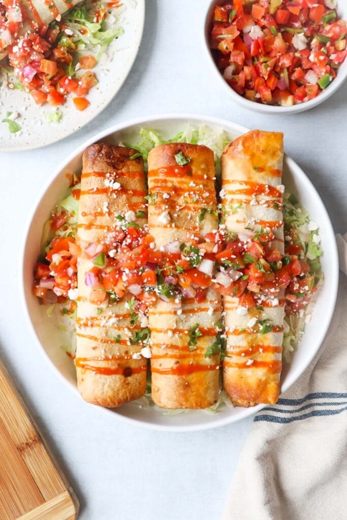 Crispy turkey taquitos topped with fresh pico de gallo, hot sauce, and crumbled cheese, showcasing a zero-waste approach to leftovers recipes.