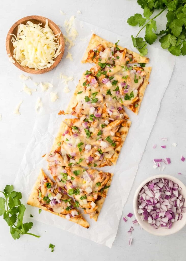 
A smoky BBQ flatbread topped with leftover turkey, melted cheese, red onions, and fresh cilantro, showcasing a zero-waste approach to leftovers recipes.