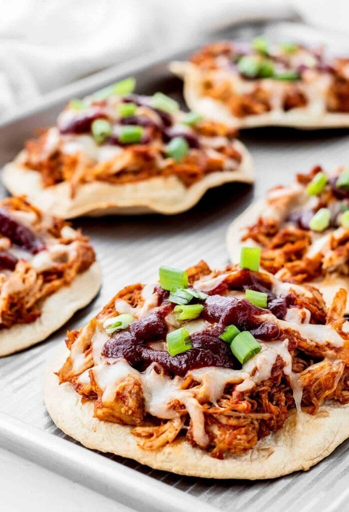 Mini BBQ tostadas topped with leftover turkey, melted cheese, cranberry sauce, and fresh green onions, showcasing a zero-waste approach to leftovers recipes.