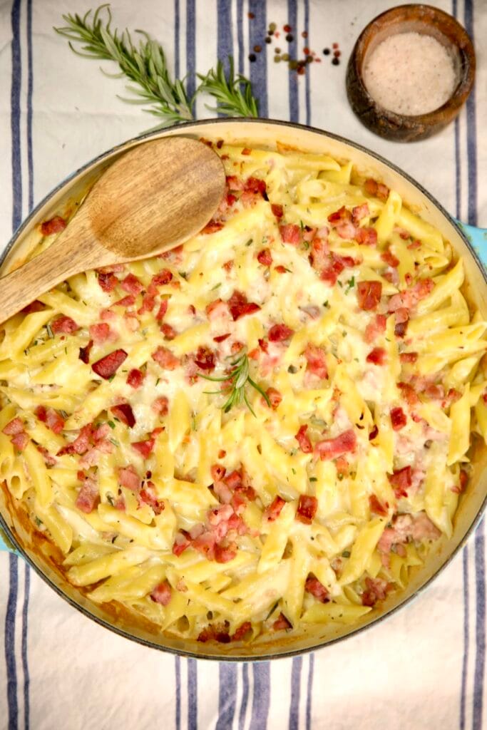 Creamy baked penne pasta dish topped with diced ham and melted cheese, garnished with fresh rosemary, perfect for quick meals with ham.