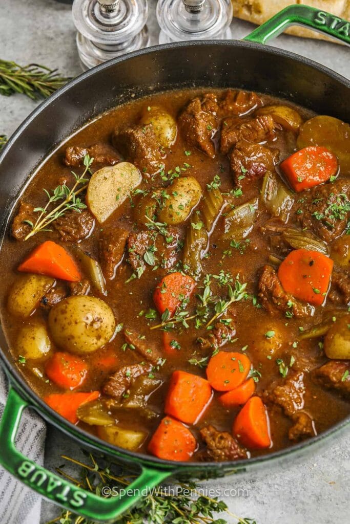 Rich and savory Irish beef stew in a cast iron pot, filled with tender chunks of beef, carrots, celery, and potatoes, garnished with fresh thyme—perfect for St. Patrick's Day food ideas and classic Irish recipes.