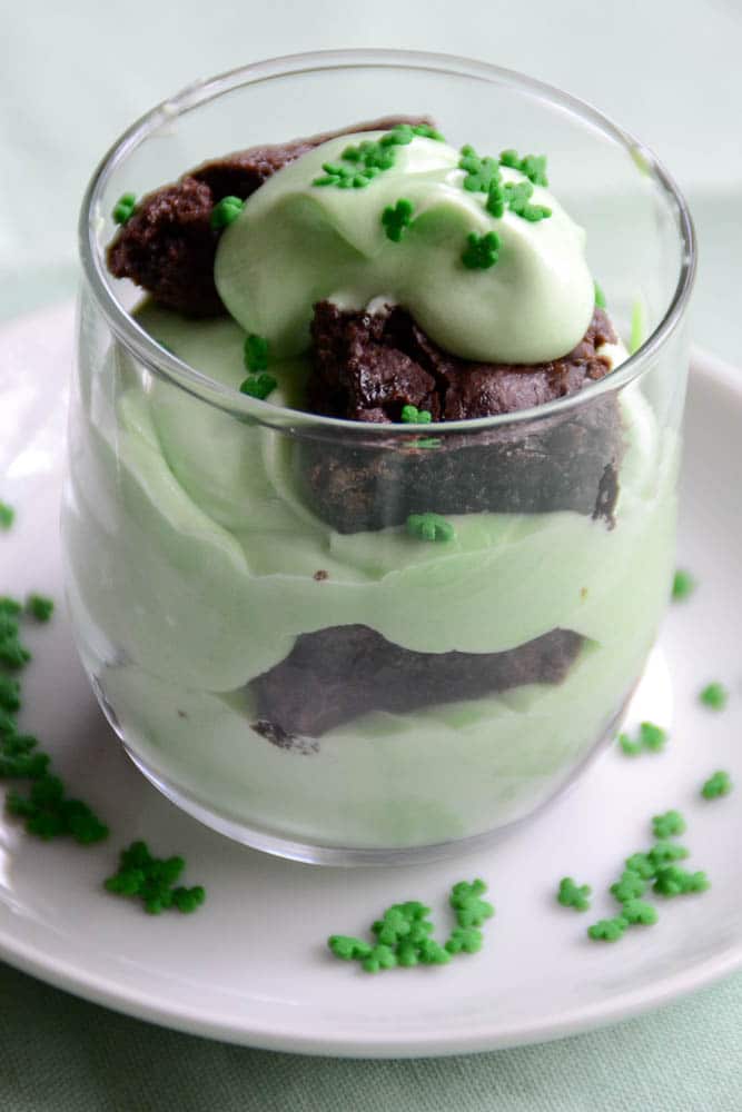 A festive St. Patrick's Day parfait layered with creamy green pudding and chunks of rich chocolate brownie, topped with whipped cream and sprinkled with tiny shamrock sprinkles. This indulgent dessert is a perfect addition to St. Patrick's Day food ideas and a creative twist for Irish recipes.