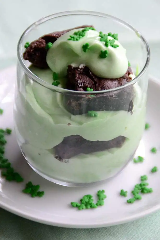 A festive St. Patrick's Day parfait layered with creamy green pudding and chunks of rich chocolate brownie, topped with whipped cream and sprinkled with tiny shamrock sprinkles. This indulgent dessert is a perfect addition to St. Patrick's Day food ideas and a creative twist for Irish recipes.