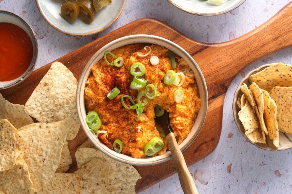 A creamy buffalo turkey dip garnished with green onions and paprika, served with tortilla chips, showcasing a zero-waste approach to leftovers recipes.