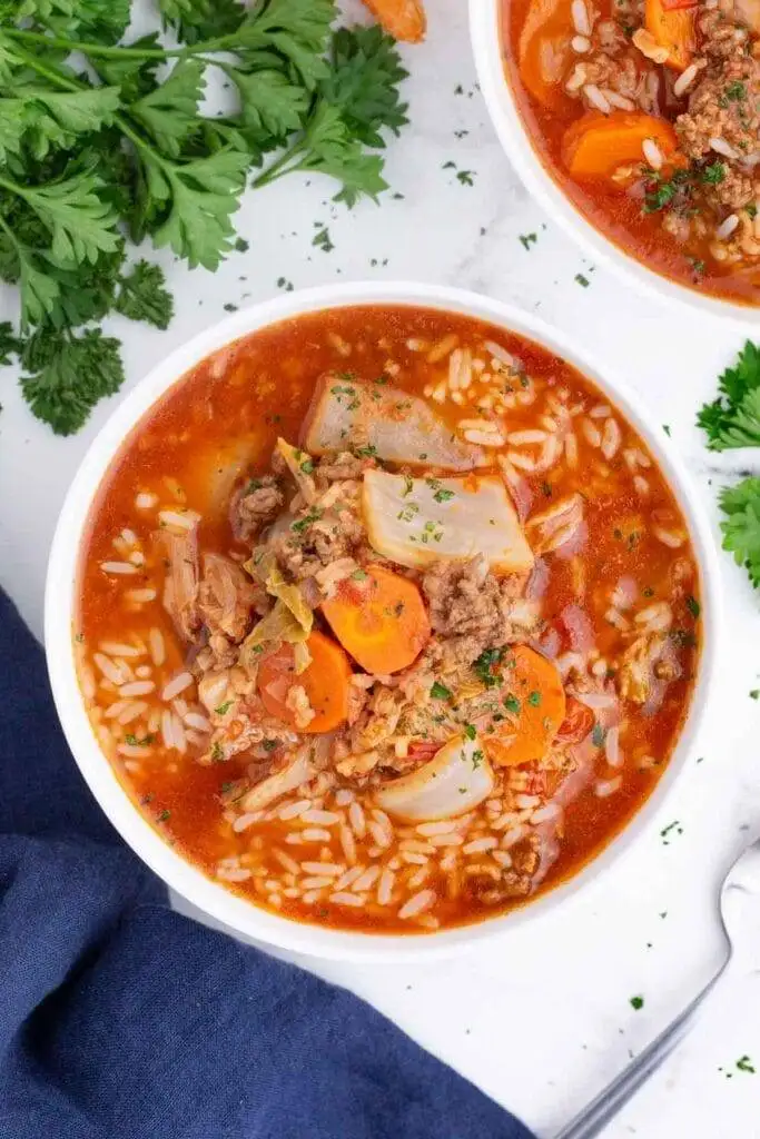 Bowl of comforting stuffed cabbage soup filled with tender rice, ground beef, cabbage, and carrots in a rich tomato broth, garnished with parsley—perfect for St. Patrick's Day food ideas and hearty Irish recipes.