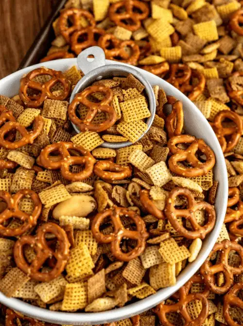 Cajun snack mix with pretzels, cereal squares, and mixed nuts served in a white bowl—an easy, spicy option for Super Bowl food ideas.