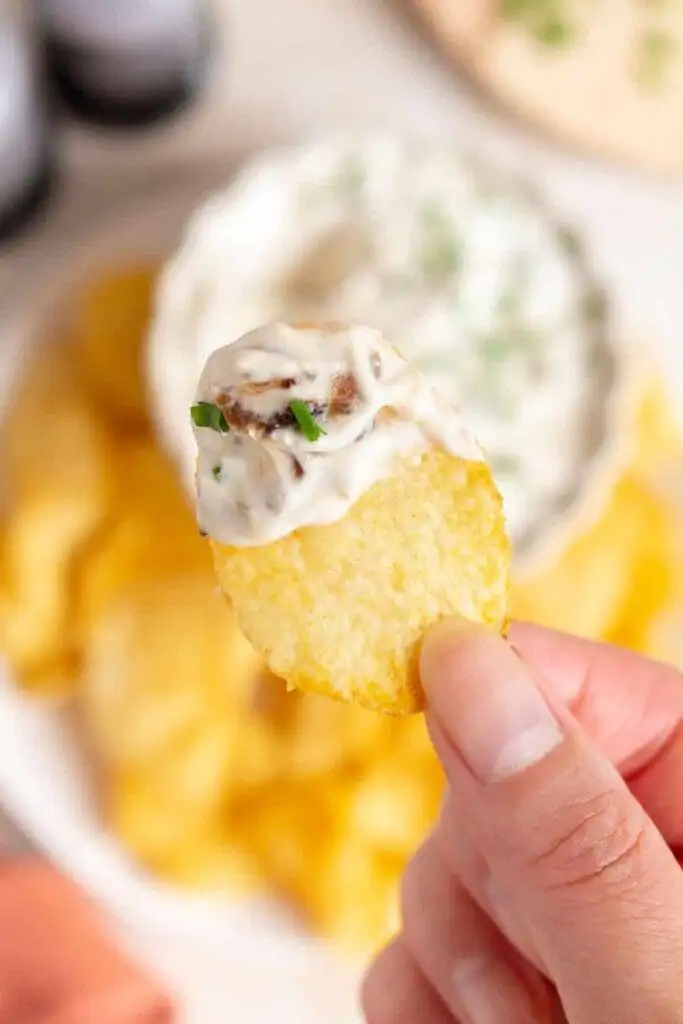 Close-up of a crispy potato chip dipped in creamy French onion dip, a classic favorite among the best party dips.