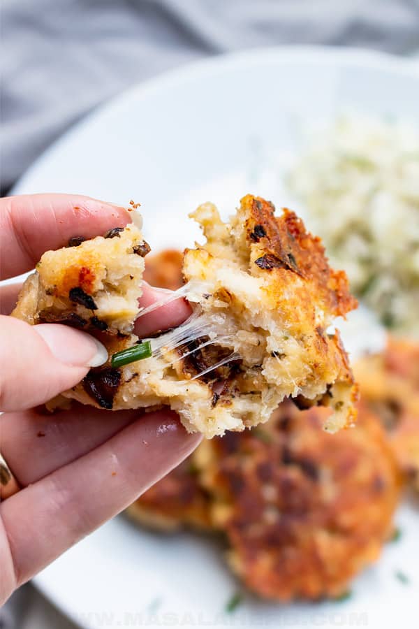 Close-up of a crispy golden-brown potato cake made from mashed potatoes, pulled apart to reveal a gooey center, perfect for leftovers recipes that turn comfort food into a delicious appetizer or side dish.