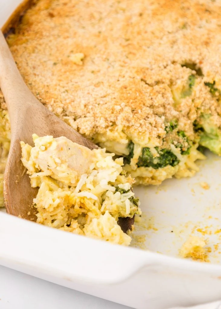 Close-up of a creamy chicken and broccoli casserole topped with golden breadcrumbs, scooped with a wooden spoon—a comforting and flavorful way to transform leftovers into a hearty dish.