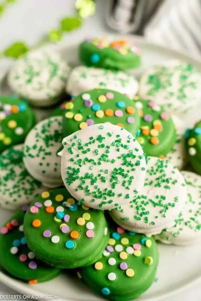 Plate of festive St. Patrick's Day cookies coated in green and white chocolate, decorated with colorful sprinkles and green sugar—perfect for St. Patrick's Day food ideas and sweet Irish-inspired treats.