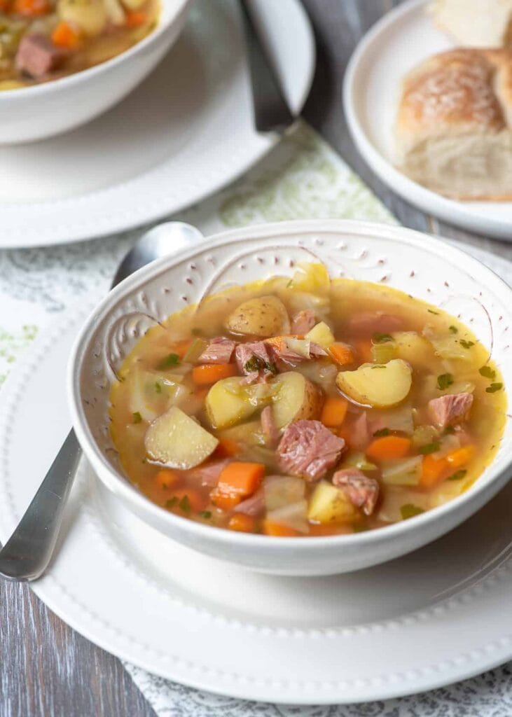 Warm bowl of corned beef and cabbage soup filled with potatoes, carrots, and tender chunks of beef, served with crusty bread—an ideal dish for St. Patrick's Day food ideas and classic Irish recipes.