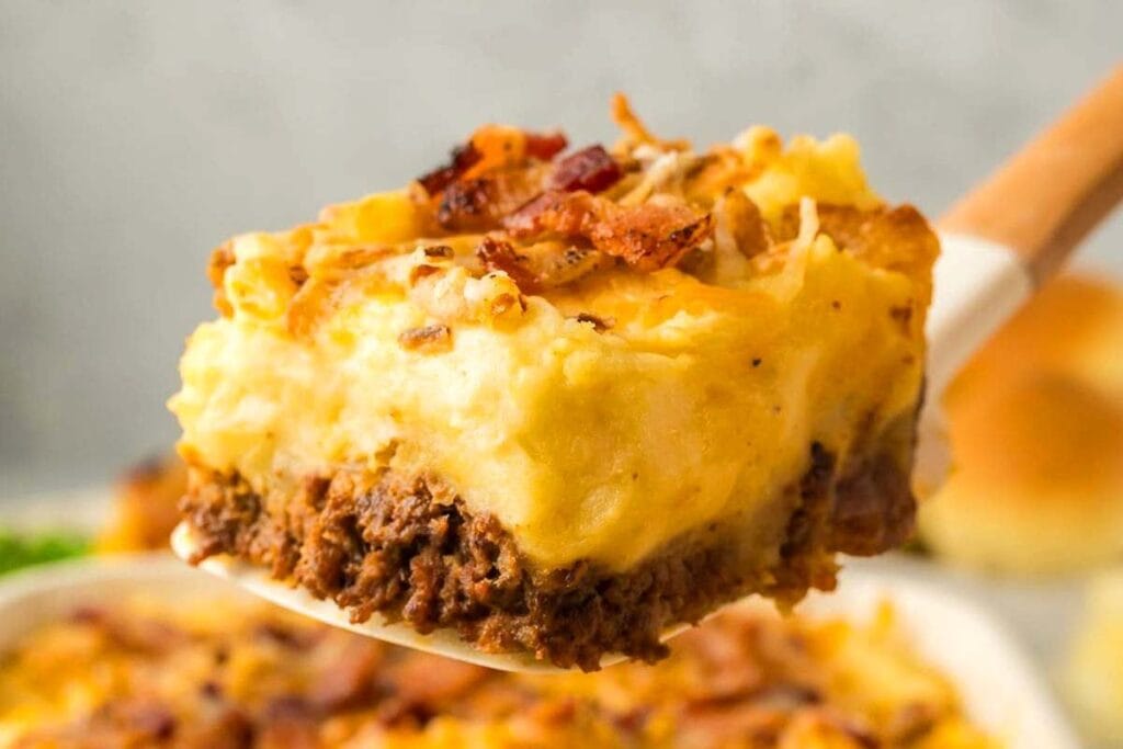 Slice of loaded shepherd's pie made with leftover ground beef, creamy mashed potatoes, melted cheese, and crispy bacon on top.