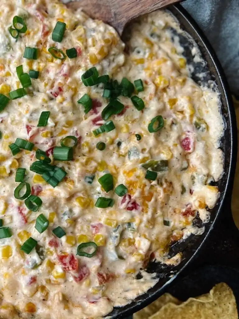 Hot and creamy corn dip with diced peppers and scallions, served in a skillet—an irresistible addition to the best party dips lineup.