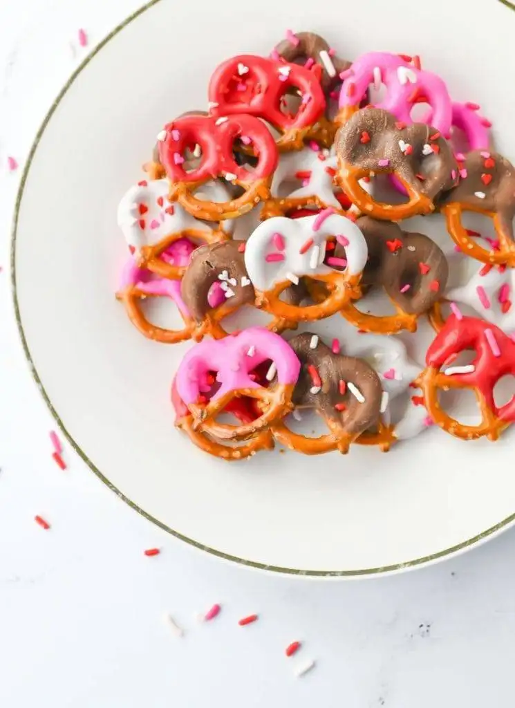 A bowl of chocolate and candy-coated pretzels with sprinkles, a colorful and easy option for romantic desserts for two.