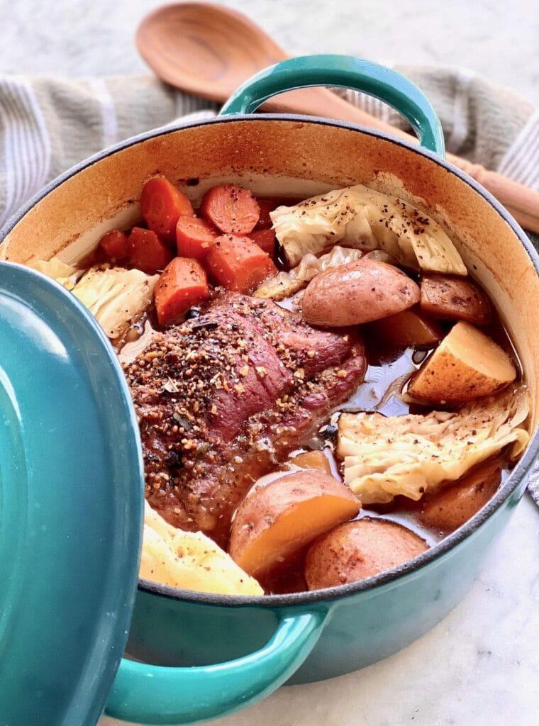 Large pot of corned beef and cabbage simmering with carrots and red potatoes in a flavorful broth, a classic dish perfect for St. Patrick's Day food ideas and traditional Irish recipes.