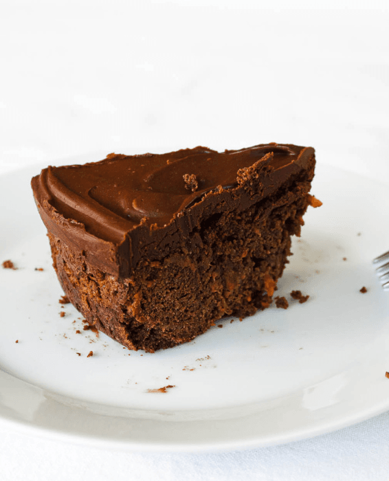 Close-up of a rich chocolate cake slice with a smooth, creamy frosting on top, served on a white plate, offering a classic and indulgent choice for Valentine's Cake Ideas.