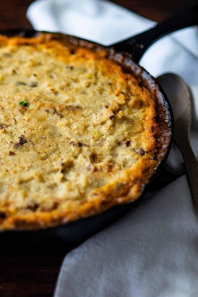 Golden-brown shepherd's pie baked in a cast-iron skillet, made with leftover ground beef and creamy mashed potatoes, served with a rustic presentation.
