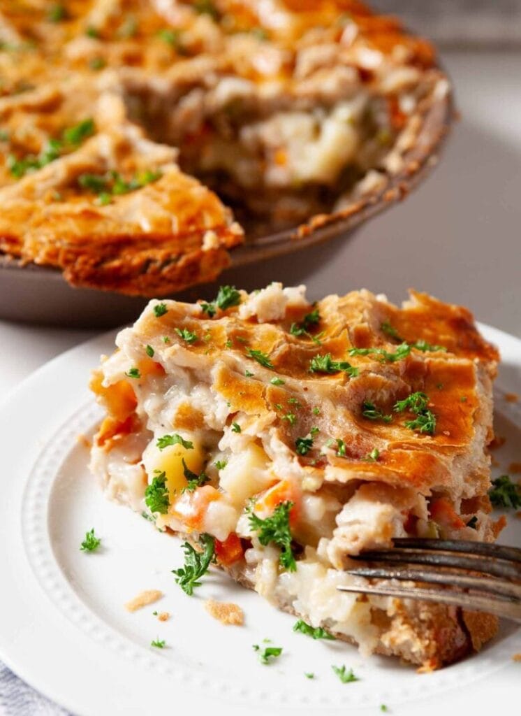 A slice of golden turkey pot pie with carrots, potatoes, and a flaky crust, showcasing a zero-waste approach to leftovers recipes.