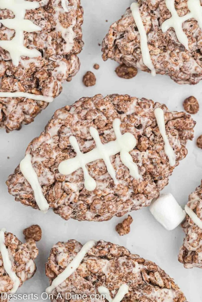 Football-shaped crispy rice treats made with chocolate and marshmallows, decorated with white icing laces. A fun and kid-friendly Super Bowl food idea for game day desserts.