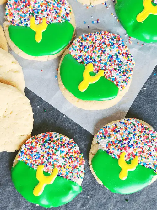 Festive football sugar cookies decorated with green icing, colorful sprinkles, and yellow goalpost designs—perfect for a Super Bowl party treat.