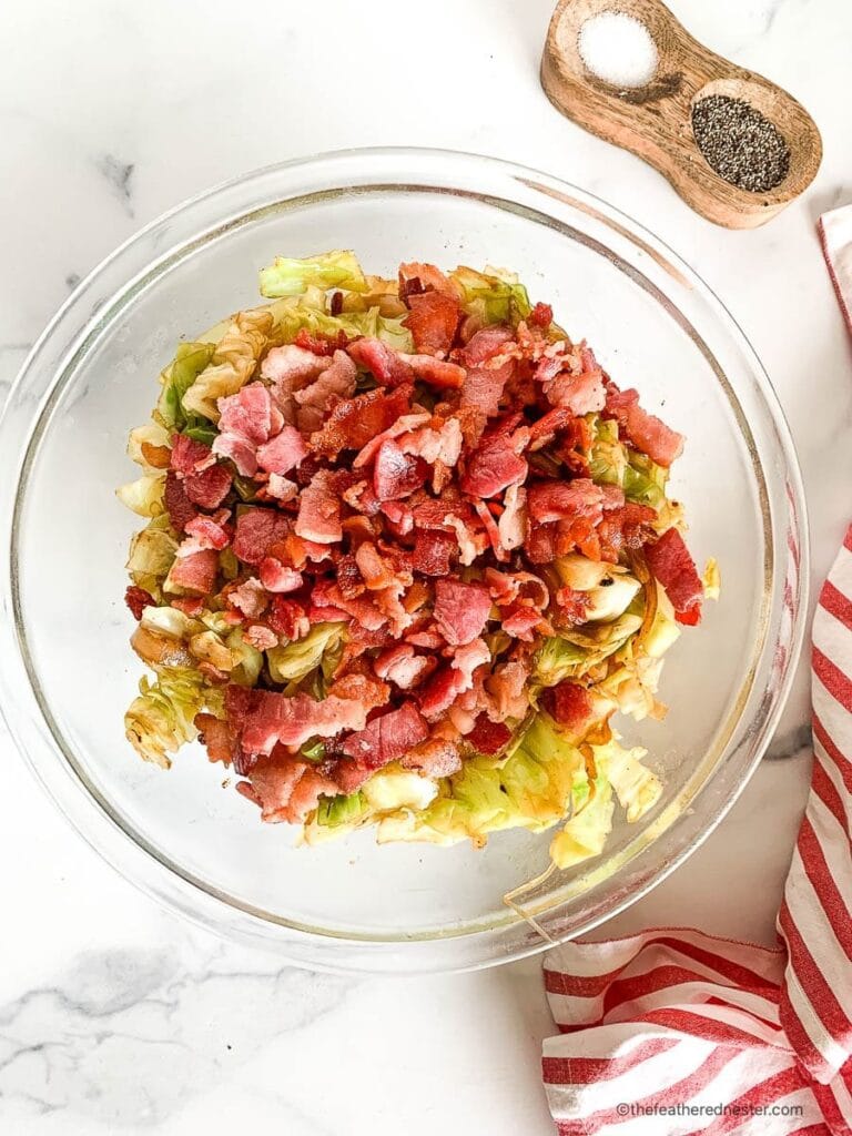 Glass bowl filled with sautéed cabbage topped with crispy bacon pieces, a simple and savory side dish perfect for St. Patrick's Day food ideas and classic Irish-inspired recipes.