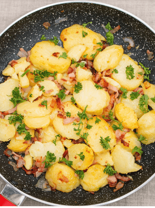 Skillet filled with golden, pan-fried potatoes mixed with crispy bacon, onions, and fresh parsley—a hearty and flavorful option for creative leftovers recipes.