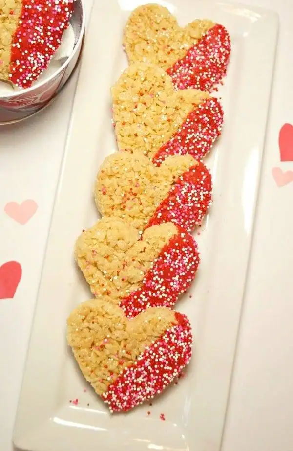 Heart-shaped rice crispy treats dipped in red icing and topped with sprinkles, a festive and delightful choice for romantic desserts for two.