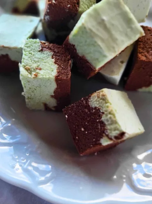 Squares of homemade chocolate and mint marshmallows arranged on a white plate, making a delightful addition to Irish desserts or St Patrick's Day treats.