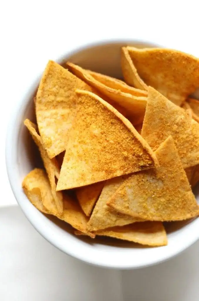 Golden, crispy tortilla chips in a white bowl, perfect for pairing with the best party dips for any celebration or gathering.