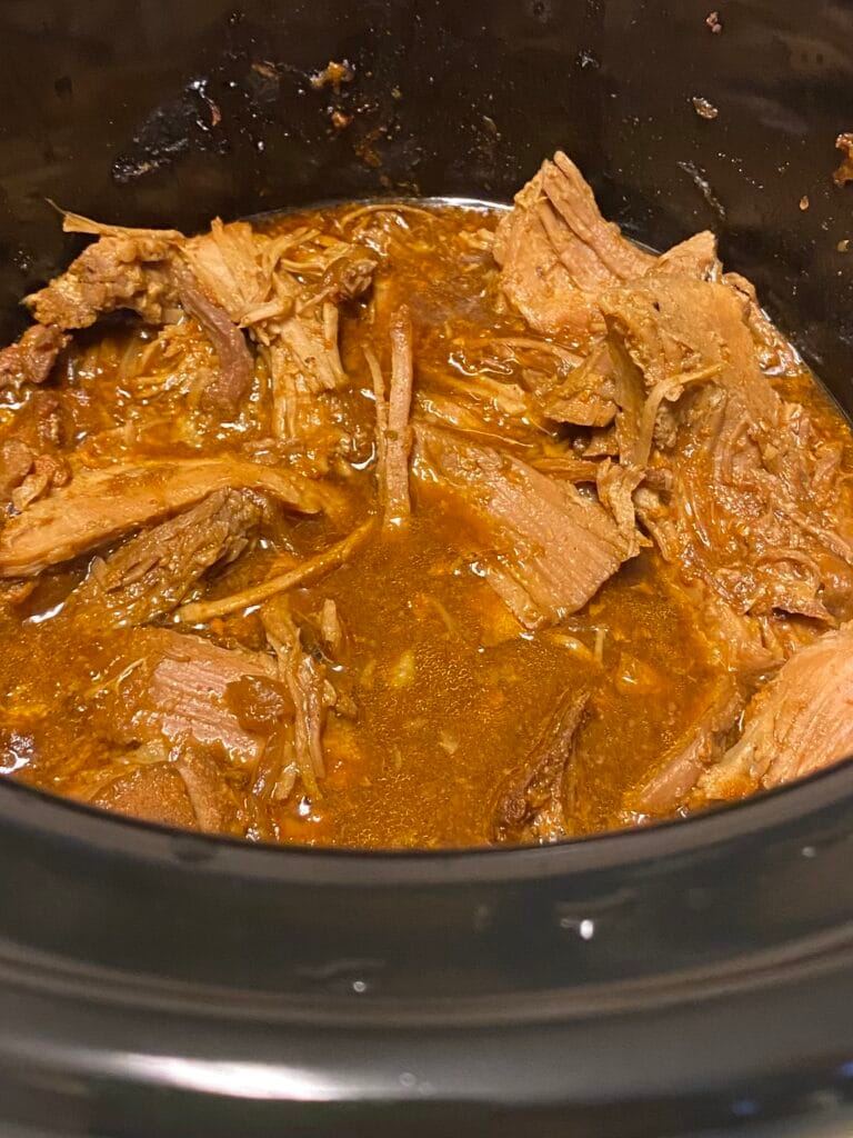 Pulled pork simmering in sauce in a crockpot.