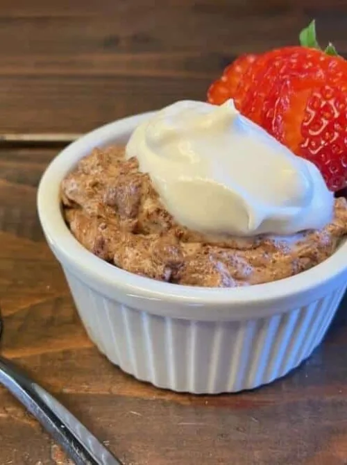 A rich and creamy chocolate mousse served in a white ramekin, topped with whipped cream and a fresh strawberry, ideal for Irish desserts or St Patrick's Day indulgences.