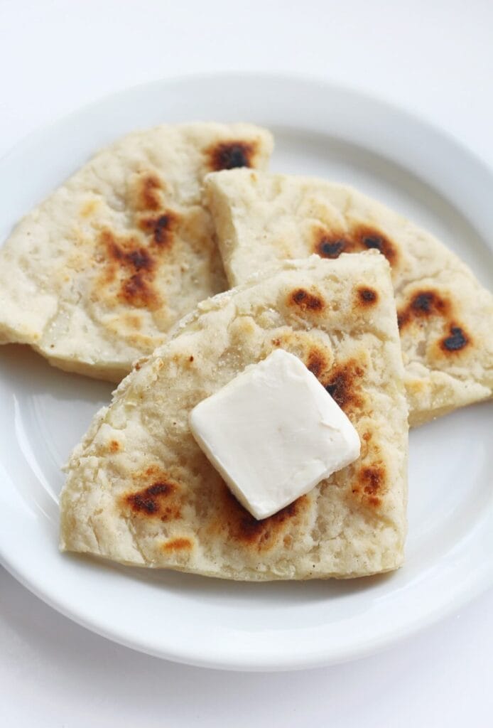 Plate of golden, pan-fried flatbreads made from leftover mashed potatoes, topped with a pat of butter—an easy and delicious option for creative leftovers recipes.