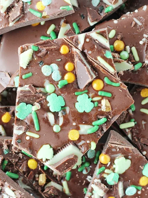 Festive St. Patrick's Day chocolate bark decorated with green, yellow, and white sprinkles, including shamrocks and candy pieces, perfect for Irish-themed desserts.