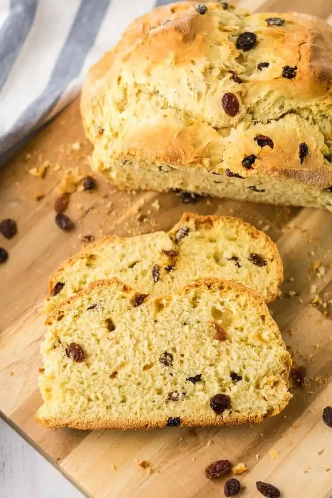 Loaf of Irish soda bread with raisins, sliced on a wooden cutting board, showcasing its golden crust and tender interior—perfect for St. Patrick's Day food ideas and traditional Irish recipes.