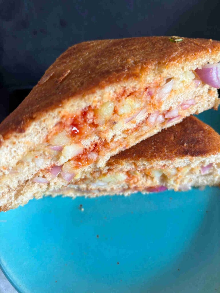 Close-up of a toasted sandwich filled with spiced mashed potatoes, onions, and a hint of chili sauce—an easy and flavorful idea for creative leftovers recipes.