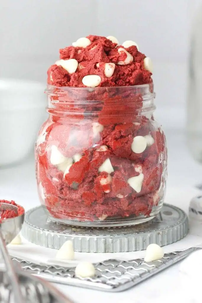 Jar filled with red velvet cookie dough and white chocolate chips, a decadent and creative option for romantic desserts for two.