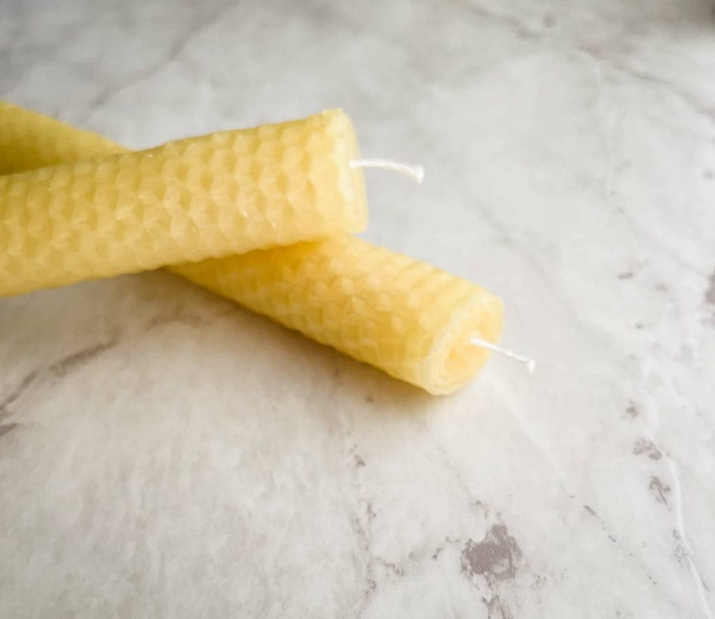 Two rolled beeswax candles with a honeycomb texture resting on a marble surface. A simple and elegant idea for DIY Valentine's Crafts, perfect for creating natural and heartfelt gifts.