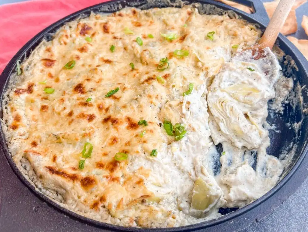 Cheesy, golden-brown artichoke dip topped with green onions, a delicious and creamy option among the best party dips for gatherings.