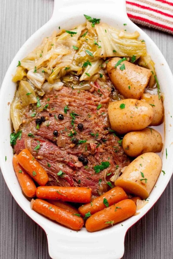 Dish of classic corned beef and cabbage with tender carrots, potatoes, and a flavorful broth, garnished with fresh parsley—perfect for St. Patrick's Day food ideas and traditional Irish recipes.