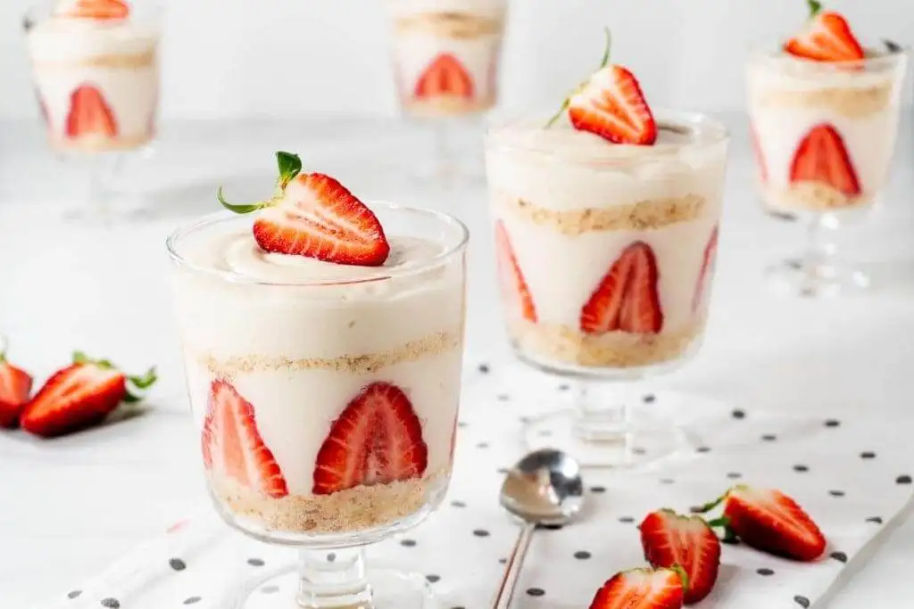 Layered strawberry parfaits in glass cups, featuring fresh sliced strawberries, creamy filling, and crumbled cookies, perfect for romantic desserts for two or a light, sweet indulgence.