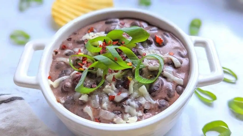 Rich and creamy black bean dip topped with melted cheese, green onions, and red pepper flakes, a bold and flavorful choice for the best party dips selection.